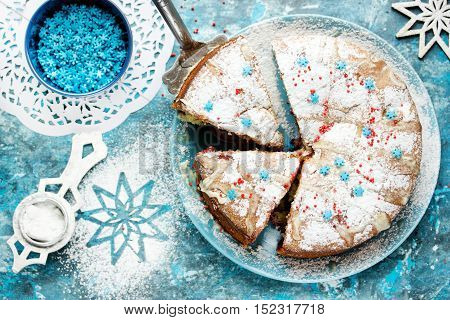 Festive Christmas winter cake with powdered sugar and snowflake sprinkling on blue background with decorations Christmas dessert recipe