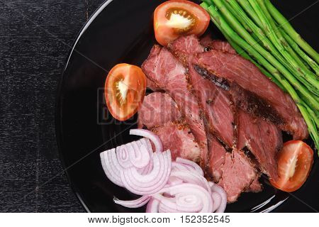 business lunch fresh roast beef meat slices on black plate wotj cutlery asparagus boiled broccoli rye bun on wooden table
