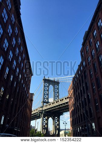 Manhattan bridge at the middle of silhouette buildings with blue sky from the Brooklyn side, Brooklyn, New York