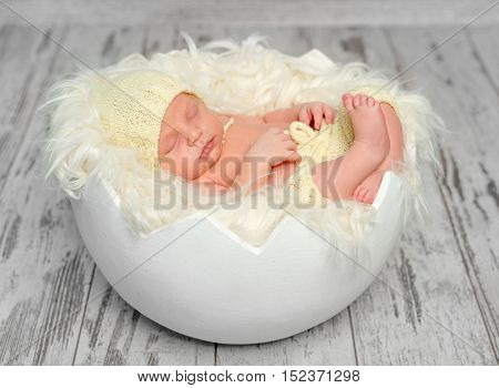 sweet newborn baby in hat and panties sleeping on round bed, top view