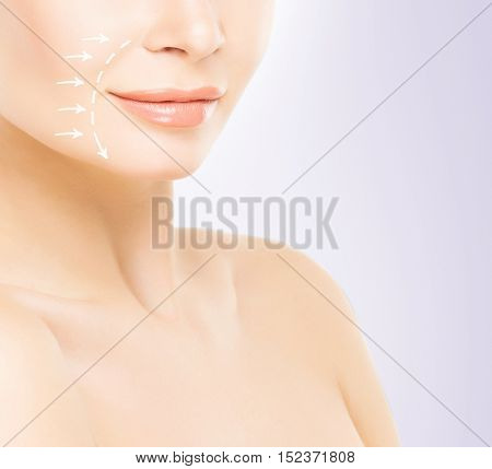 Close-up half face portrait of young, attractive woman with arrows on her face. Face lifting concept.