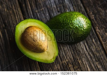 Fresh Avocado sliced over vintage wooden background close up. Ripe green avocado fruit on wood board.