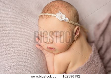 lovely sleeping newborn girl with flower on her headband with hand under her head