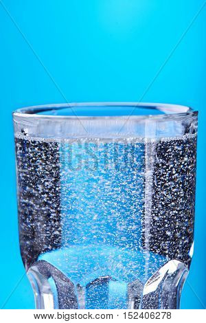 water in glass with bubbles at a blue background. Close view
