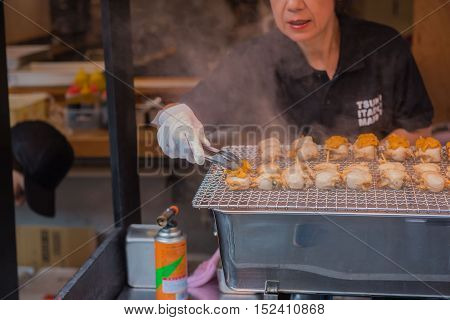 TOKYO  , JAPAN - OCTOBER 12 ,2016 : Tsukiji Market  , Tokyo, Japan. October 12 2016
Chefs are cooking grilled shell at Tsukiji market.