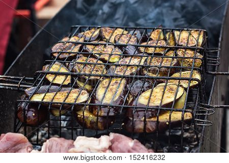Fresh healthy eggplant or aubergine preparing on a barbecue grill over charcoal. Grilled aubergines eggplants slices. Vegetarian, Mediterranean cuisine. Delicious Food, vegetables on bbq party.
