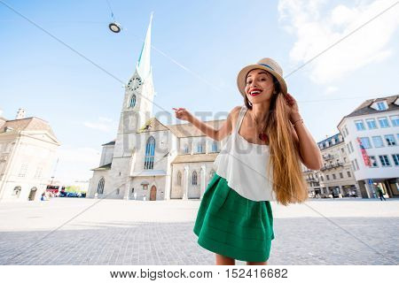 A portrait of a young female tourist in front of the famous church in the center of Zurich city. Having happy vacations in Switzerland