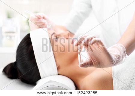 Cosmetic ampoule, a woman in the beauty salon, vitamin C in cosmetic ampoule.