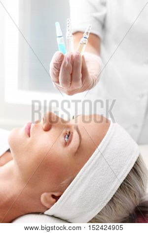 Cosmetic ampoule, serum applied to the face of a woman.
Hand beauticians shows an ampoule with a cosmetic preparation