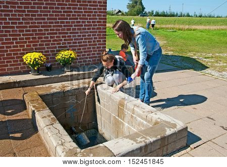 KUREMAE, IDA-VIRUMAA COUNTY, ESTONIA - AUGUST 21, 2016: Young women  take water from The Holy Spring on the place of Marian apparition. Located not far from Puhtitsa Orthodox Dormition Convent