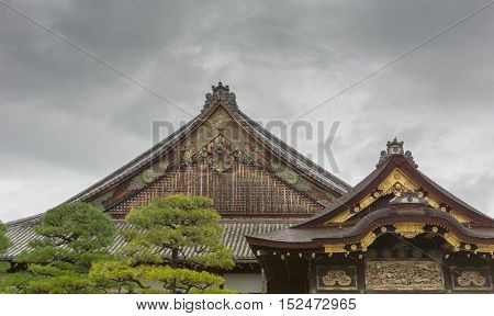 Kyoto Japan - September 19 2016: The roof structure of the Ninomaru Palace buildings at Nijo Castle. Two roof crests are different since one is recently repainted and its gold plates polished. Cloudy sky couple of trees.