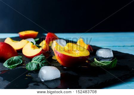 Slices of ripe nectarines and peaches on black stone background. Fresh fruit background. Nectarines and peaches as healthy eating concept. Selective focus.