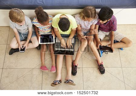 Overhead Shot Of Children Sitting On Floor Using Technology