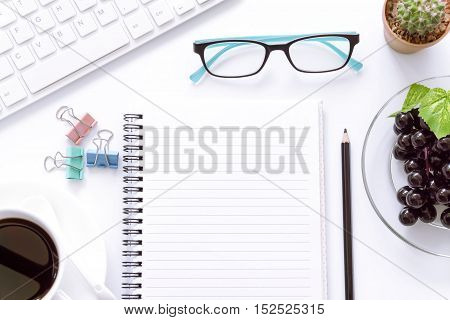 Office desk top view with keyboard, laptop eyeglasses,coffee cup. and book / Office supplies Blank and pen notebook on white background.
