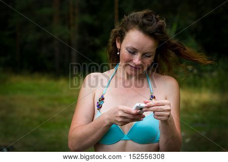 Girl In Bathing Suit In The Forest And Cell Phone