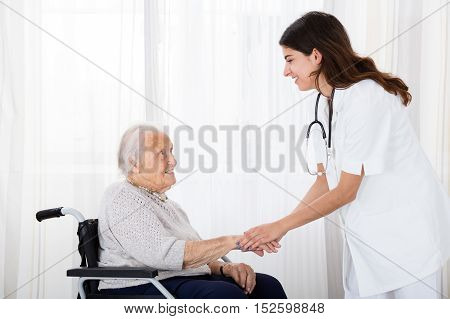 Female Doctor Consoling Disabled Senior Patient On Wheelchair In Hospital