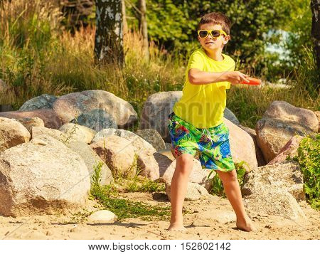 Play and fun concept. Little playful enjoyable boy kid throwing frisbee disc. Male child having fun playing outdoor on beach.