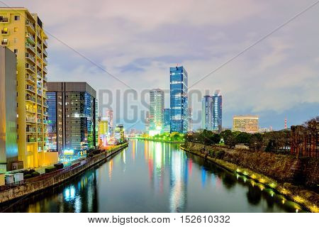 Osaka business park with city buildings and river at night time