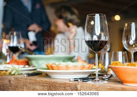 Wine glass on celebration table with people unfocused on background. Close up view.