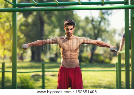 Well built muscular man doing a physical exercise outdoors