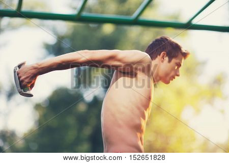Well built muscular man doing a physical exercise outdoors