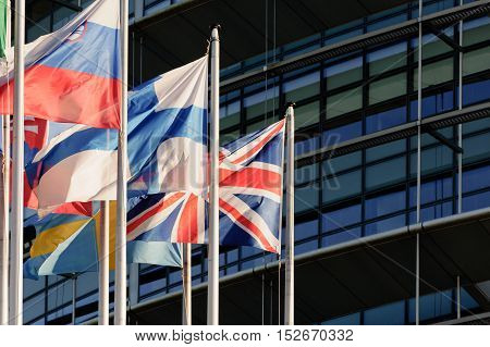 United Kingdom of Great Britain and Northern Ireland or Union Jack flag against front glass facade of European Parliament