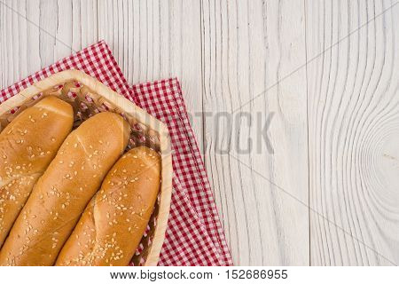 Buns in a wicker basket on old wooden table. Top view.