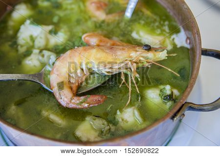 Arroz de Tamboril or soupy seafood rice portuguese recipe. Spoon holding a prawn