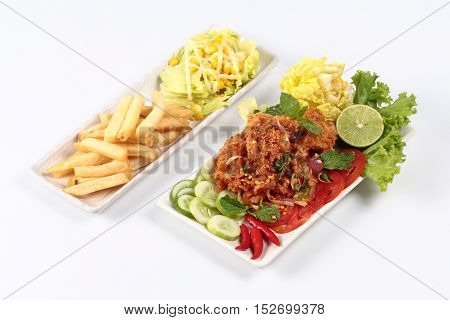 Spicy fried chicken salad (Yum Kai Zap in Thai) as spicy chicken salad,chili,tomato,red onion,roasted rice,dried chili ,Chinese cabbage,lettuce,peppermint ,cucumber and green lemon juice served with mixed vegetables salad and french fires.