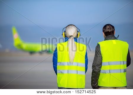 airport workers looking at an airplane as it departures