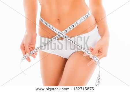 Close up photo of slim woman measuring her waist's size with tape measure