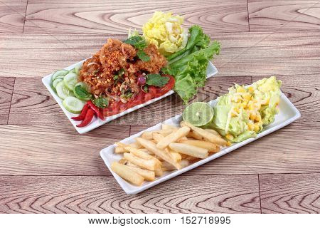 Spicy fried chicken salad (Yum Kai Zap in Thai) as spicy chicken salad,chili,tomato,red onion,roasted rice,dried chili ,Chinese cabbage,lettuce,peppermint ,cucumber and green lemon juice served with mixed vegetables salad and french fires.