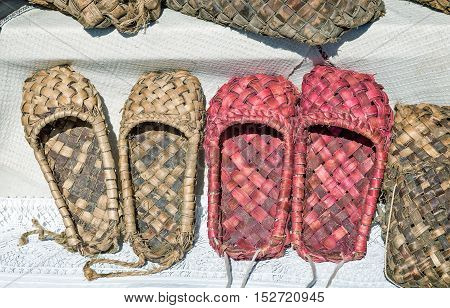 Demonstration of ancient objects of rural life: woven from tree bark sandals. Shoes of the peasants in ancient Russia.
