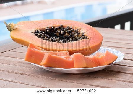 Papaya slices on a plate on the pool background