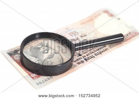 Indian Currency Rupee Note with magnifying glass isolated on white background