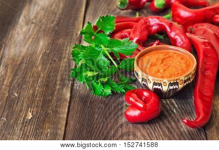 Homemade sauce and red hot chili peppers and celery on rustic wooden background. Selective focus.