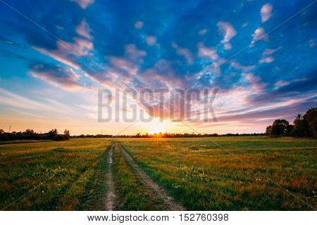 Sunset, Sunrise Over Rural Meadow Field. Bright Dramatic Sky And Country Road Path Way. Countryside Landscape Under Scenic Summer Dramatic Sky In Sunset Dawn Sunrise. Skyline.