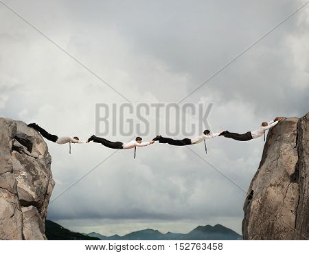 Businessmen working together to form a bridge between two mountains