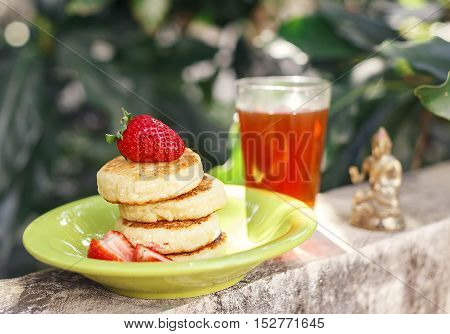 Sweet ricotta pancakes with strawberry and tea in the garden sunny day