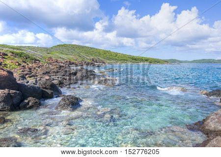 Small waves of clear turquoise water roll against rocky beach of Soldier's Point on Caribbean island paradise of Isla Culebra in Puerto Rico