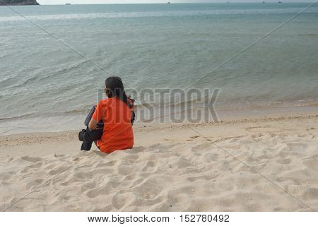 young woman sitting on the beach and looks at sea in relaxing holiday