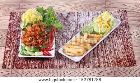 Spicy fried chicken salad (Yum Kai Zap in Thai) served mixed vegetables salad and french fires.