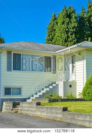 Entrance of family house with concrete doorsteps and asphalt driveway in front