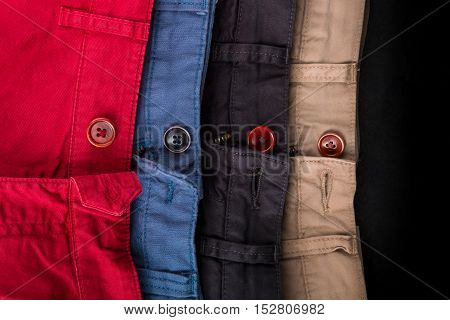 Fragment Of Four Cotton Twill Pants Red, Blue, Black, Beige With Open Buttons. Close Up.