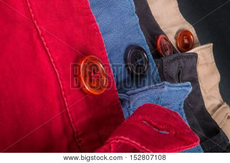 Fragment Of Four Cotton Twill Pants Red, Blue, Black, Beige With Open Buttons. Close Up.