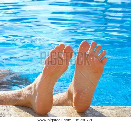 Pés de homens, felizes na piscina.