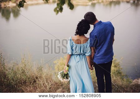 A Wedding By The Sea. Honeymoon. The Bride And Groom Hugging On The Shore Of Lake. Groom And Bride H