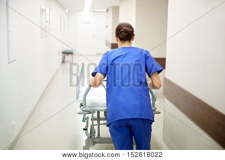 people, healthcare, reanimation and medicine concept - nurse carrying hospital gurney to emergency room