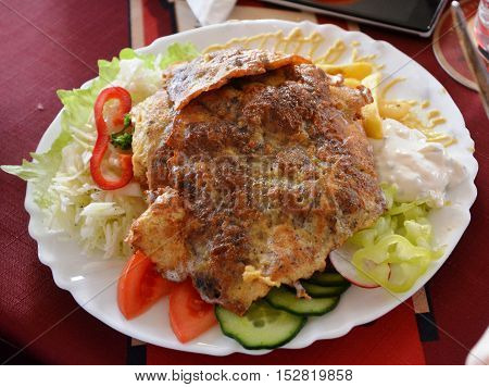 Chicken breast coated in batter and fries on a plate