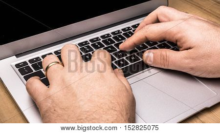 Person working on laptop computer on wooden table